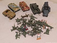 Overview of five die-cast vehicles and pile of plastic soldiers