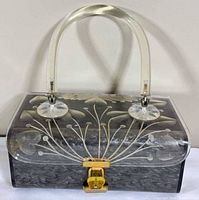 Front view showing floral-etched lid, marbled base, handle, and latch