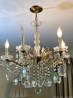 full view of illuminated six-light crystal and brass chandelier