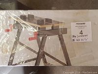 Photo of the boxed Jobmate folding work bench showing a side view of the folded bench with visible red clamp handle.