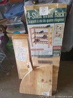 Boxed solid pine 4-shelf wine rack pieces with packaging showing product image and dimensions.