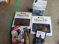 Photo showing all items in lot together on floor including timer box, tile boxes, drill bits, and paint tools