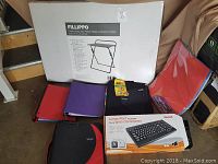 Overall lot showing folding laptop tray box, Maxell large print keyboard box, colored binders, and foam sheets.