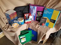Photo showing Five Star binders and folders in green and blue, Maxell DVD-R spindle stacks, Staples 9x12 manila envelopes, Dynex multicoloured binder/storage plastic cases, and a Microsoft web camera in retail box