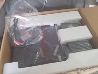 View of the electronic device with packaging showing the turntable and some cables wrapped in plastic.