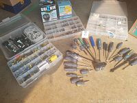 Overall lot showing organized boxes of screws, bolts, and anchors beside an array of screwdrivers.