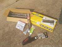 Lot of tools and adhesives including the tile cutter in box, Husky hangall, tubes of sealer and glue, and packaged tub surround.