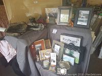 Photo showing left and right handed baseball gloves, various picture frames, boxed keyboard accessory, and assorted small decor on cloth covered table.
