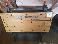 Folded view of Workmate 400 workbench showing wooden top with branding and metal frame underneath.