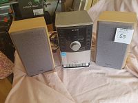 Sony CMT-EH10 micro HI-FI component with two wooden speakers with grey fabric grills, set on a light-colored cloth.