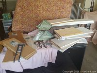 Various multi-purpose shelves stacked on a covered surface, showing white and natural wood boards and green Rubbermaid hooks.