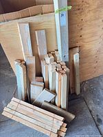 Bundle of assorted lumber offcuts and plywood sheet leaning against box