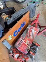 Lot overview showing Curtis creeper, pair of jack stands, boxed MotoMaster jack, two wheel chocks