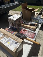 Overall lot on table showing boxed SideKick dryer, pump kit, grease gun box, duster and hand tools