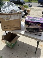 Original Sidewind car cover box and contents on table