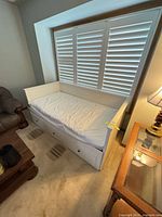 Full view of white twin daybed with mattress and drawers