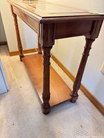 Angled side view of console table showing top glass panels, turned legs and lower shelf