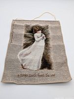 Full view of woven tapestry with hanging cord and visible inscriptions