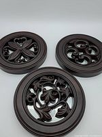 Three circular mirrored plaques with carved overlays displayed front view