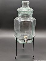 Full view of glass beverage dispenser on metal stand