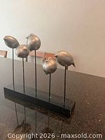 Full view of five metal birds on wooden base
