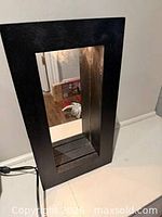 Front view of rectangular mirror with slatted light section and power cord