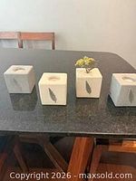 Four stone cubes lined on countertop showcasing tealight recesses and feather motif