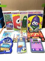 Group shot of all items: four VeggieTales puzzles, two Futurama calendars, Harry Potter calendar, Wall-E magnetic play set, Toy Story appliqués, Discovery Kids tablet