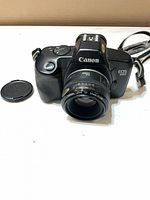 Front view of Canon EOS 850 with EF 50mm lens and cap beside