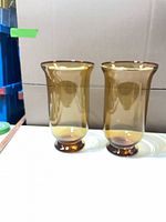 Pair of amber glass vases standing side by side showing full shape