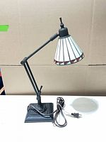 Full view of adjustable lamp showing metal body and leaded glass shade
