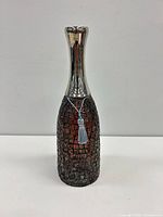 Front view of vase showing mosaic body, metal neck, tassel