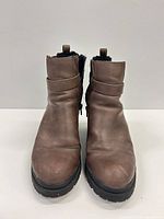 Front view of brown faux leather ankle boots showing toe shape, side buckle strap and overall wear