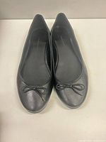 Top view of both black ballet flats showing bow detail and toe condition