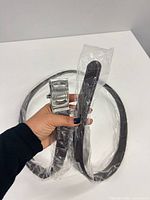 Belt coiled in packaging, buckle visible