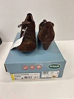 Front view of brown suede lace-up booties on original box showing size label