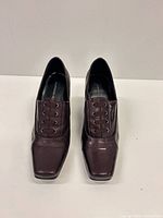 Front view of both burgundy lace-up pumps showing square toes and lacing detail.