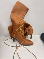 Side view of both tan leather lace-up boots showing stud trim and laces