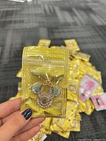 One packaged gold-tone crystal phone ring grip held in hand