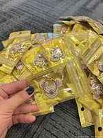 Hand holding sealed pouch showing gold-tone rhinestone phone ring holder