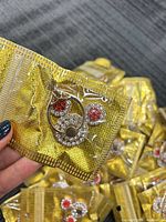 Close-up of one sealed gold-tone rhinestone phone ring grip stand in gold pouch