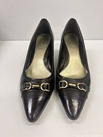 Top view of both pumps showing leather finish, pointed toes and gold-tone horsebit detail
