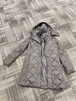 Full view of charcoal quilted puffer coat laid flat
