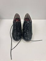 Front view of both shoes showing lacing, patent leather finish and brogue detailing