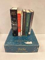 All six books standing on Trivial Pursuit box