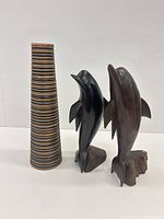 Front view of two dolphin sculptures and striped cylinder