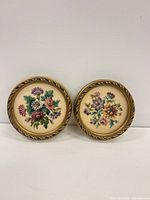 Both round floral needlepoints side by side