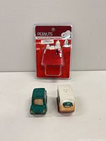 Front view showing Snoopy doghouse shaker in packaging, green sedan and camper van shakers