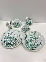Front angled view showing pattern on stacked plates, cups, saucers, creamer and shakers
