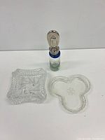 All three visible items: square ashtray, three-lobed dish, glass bottle with stopper